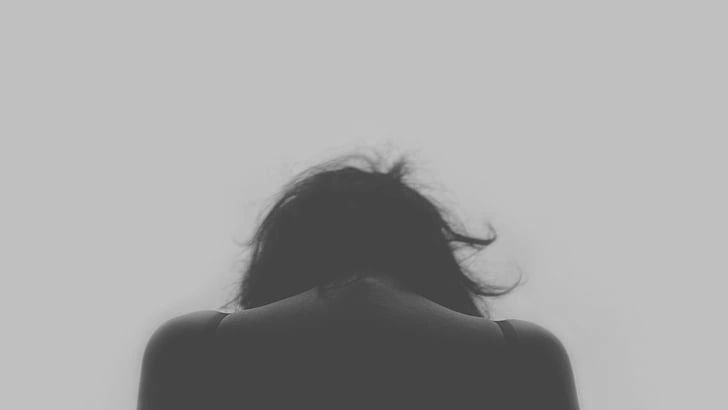 Silhouette of a person with head bowed against a gray background.
